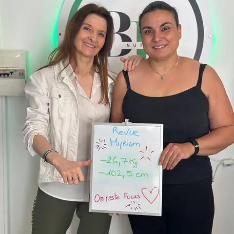 Une membre sourit en montrant les chiffres de son bilan sur l’ardoise