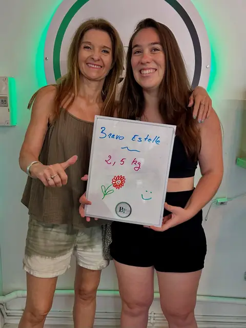 Une membre sourit en montrant les chiffres de son bilan sur l’ardoise